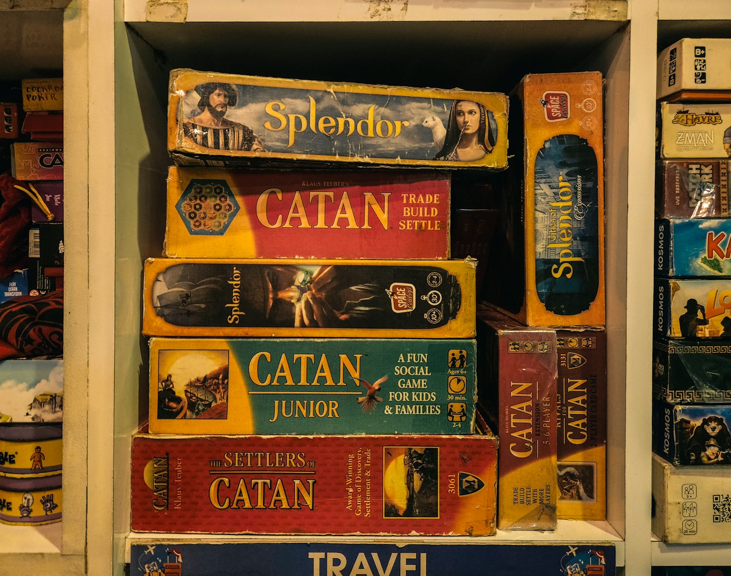Drevená polica plná krabíc doskových hier Catan a Splendor.